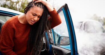Female Motorist With Head Injury Getting Out Of Car After Crash