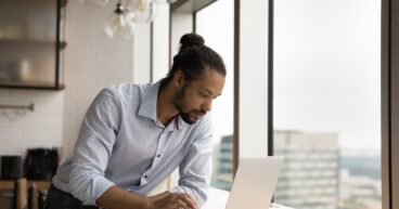 Serious biracial man work on computer at workplace