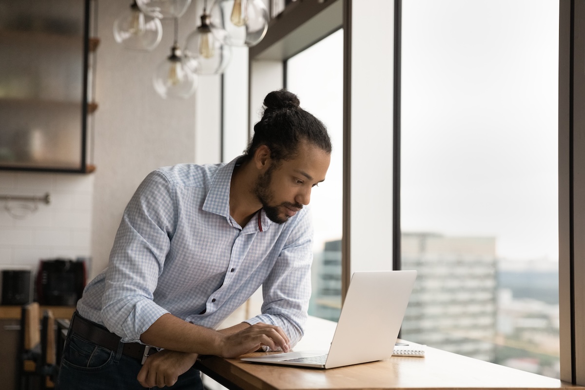 Serious biracial man work on computer at workplace