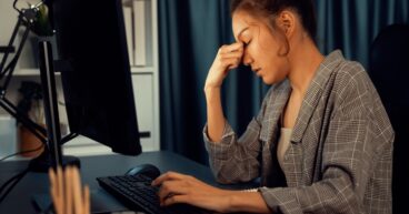 Businesswoman working on computer with stretching arm up at night. Infobahn.