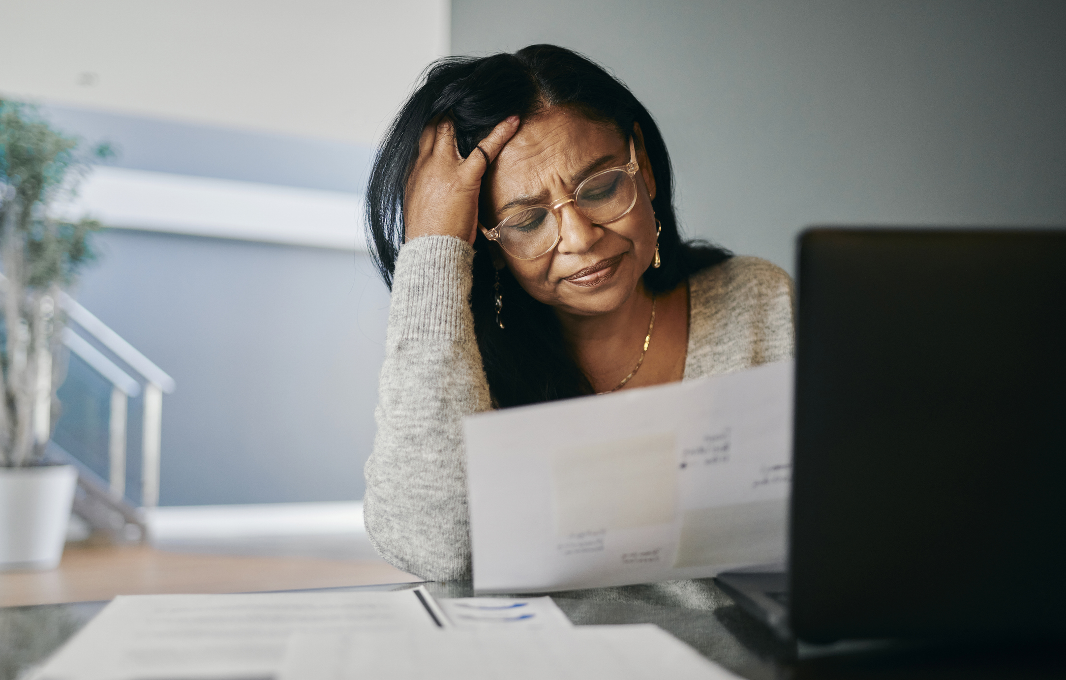 Stressed Mature Woman Managing Pension at Desk, Looking Worried